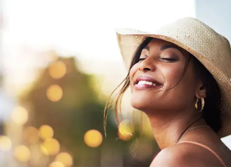 Cosmetic wrinkle treatment shown with smiling woman enjoying youthful, glowing skin in natural sunlight.
