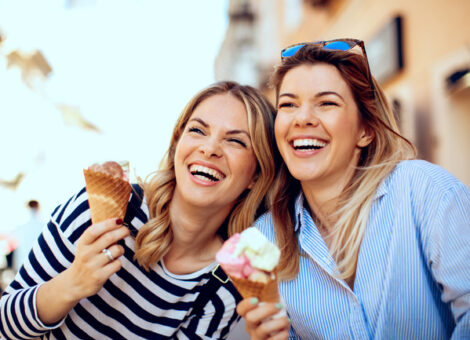 Metabolism-boosting medication results shown by two happy women enjoying ice cream and laughing outdoors.