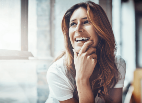 NAD+ IV therapy benefits reflected in a happy woman smiling and relaxing by a bright window.