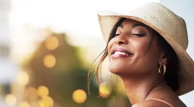 Cosmetic wrinkle treatment shown with smiling woman enjoying youthful, glowing skin in natural sunlight.