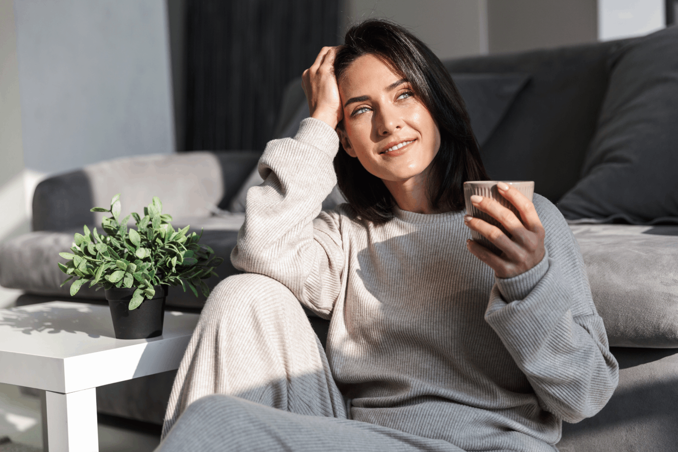 Woman in sweat pants drinking coffee at home after taking hormone therapy for women.