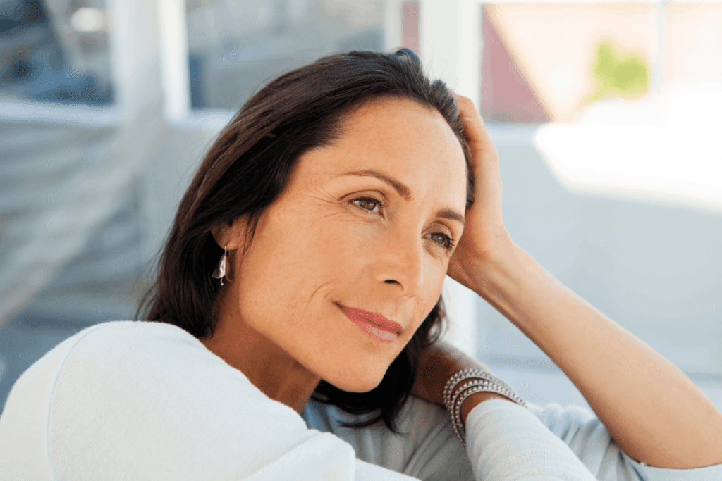NAD infusion results portrayed in a calm woman gazing thoughtfully while resting indoors.