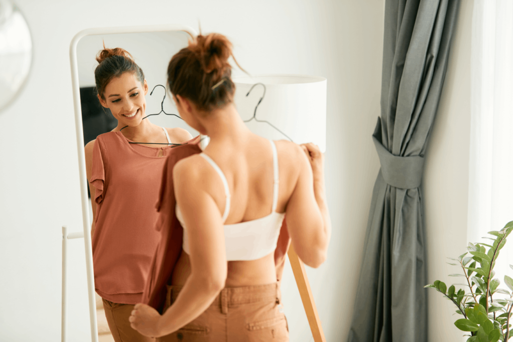 Smiling woman trying on clothes, potentially seeing results from a peptide therapy clinic.
