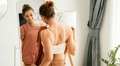Medical fat burners results illustrated by a woman smiling confidently while trying on clothes in front of a mirror.