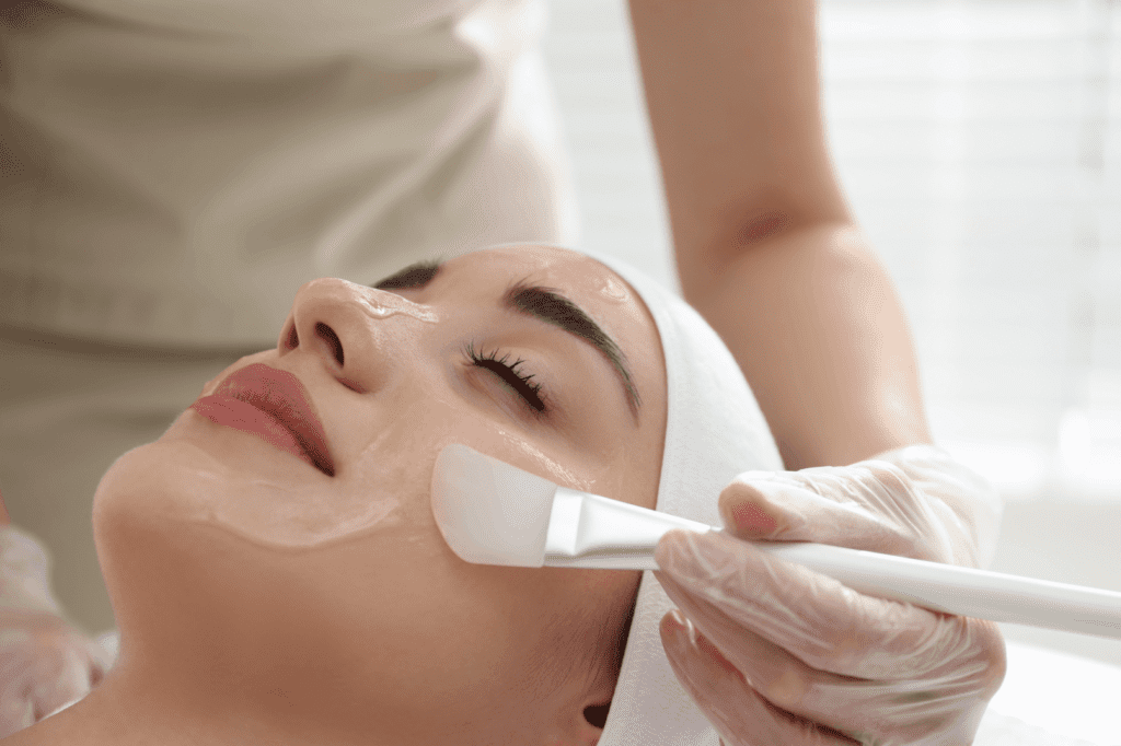 Aesthetician applying one of the best peels for hyperpigmentation to a woman's cheek.