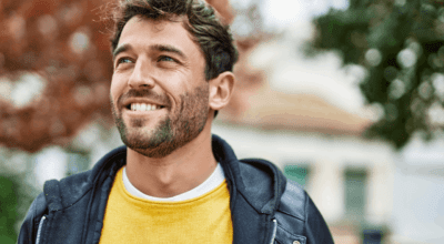 man walking outside in a yellow shirt and coat after using hormone therapy