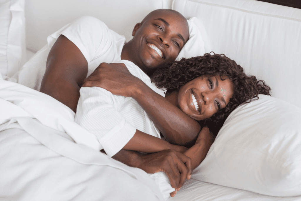 Happy couple cuddling in bed, possibly benefiting from hormone imbalance treatment.